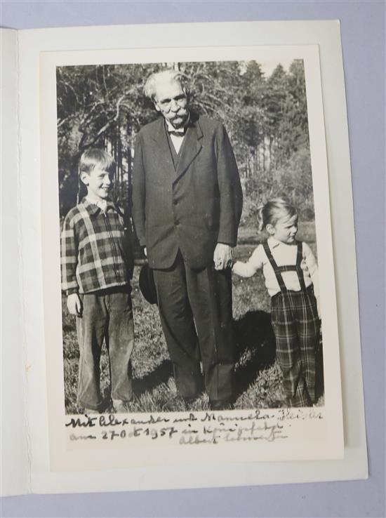A black and white photograph of Albert Schweitzer standing with two children, apparently dated 27th October 1957 with card